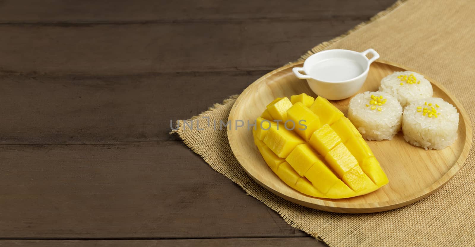 Yellow half  mango with small fork. Mango fruit cubes on the wooden table. Tropical fruit asia. Fresh yellow mango peel and Sliced cubes on wood butcher. Dessert fruit.
