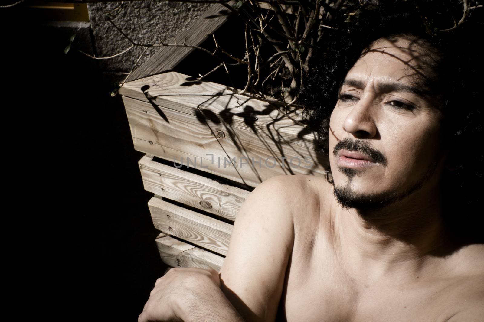 Portrait of latin man with beard and curly black hair. Naked torso