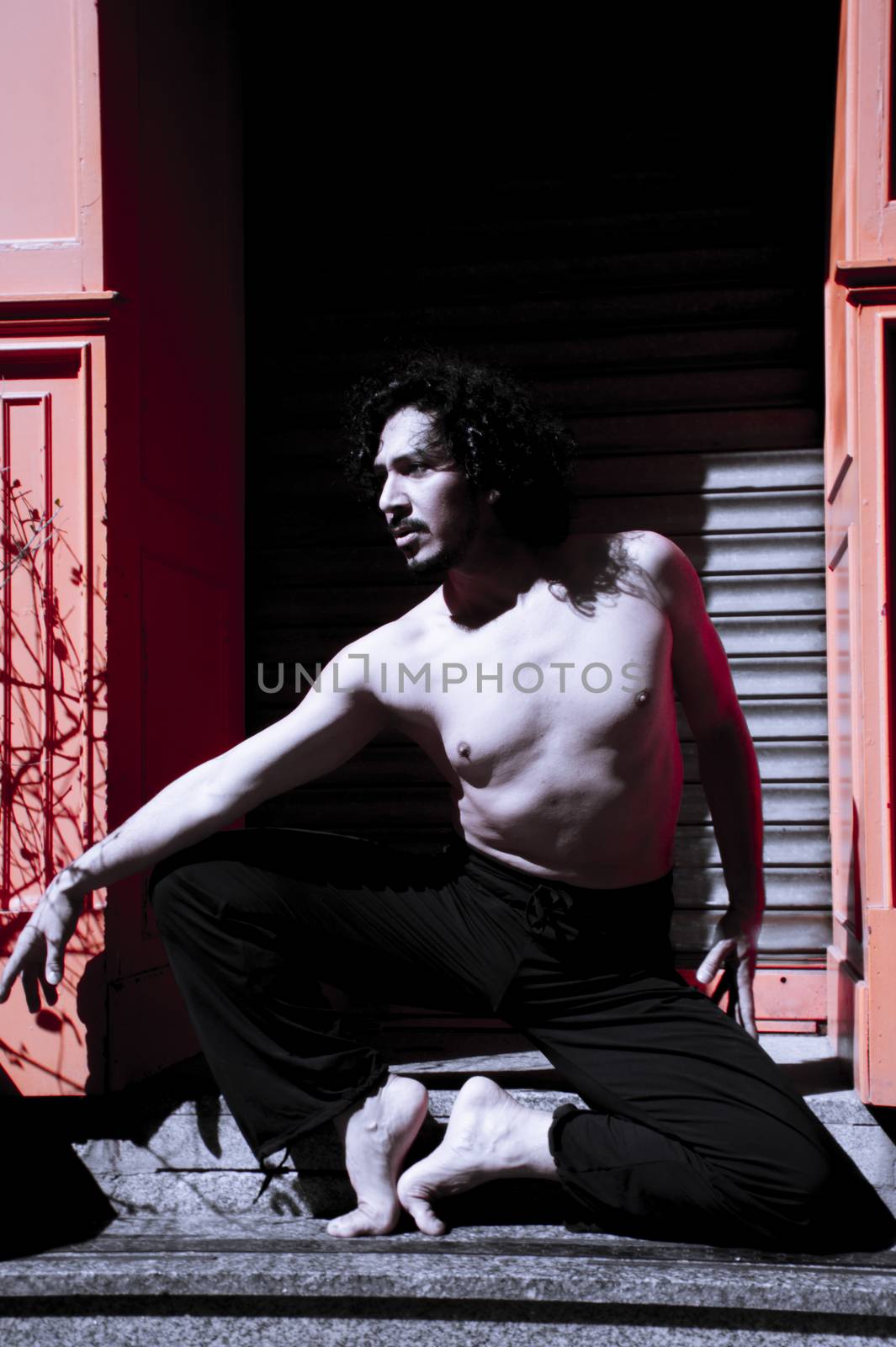 Latin male dancer posing with dancing figures. Urban background