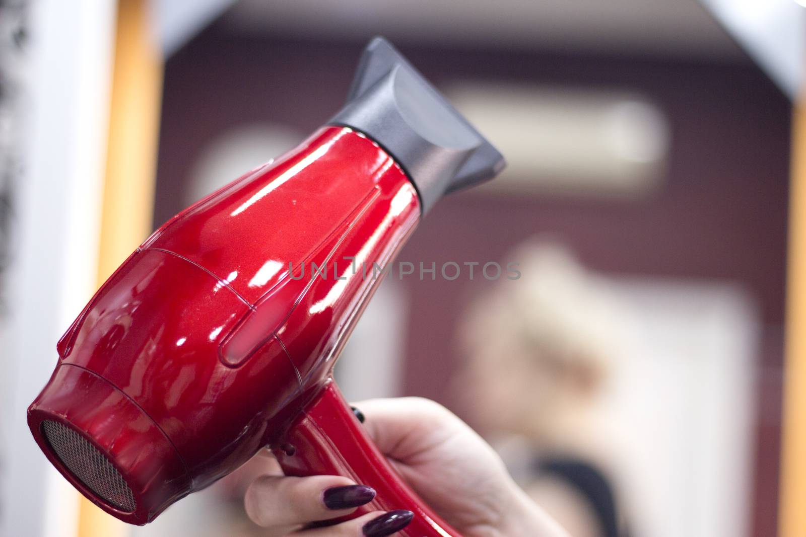 Hairdresser drying hair with red hand dryer