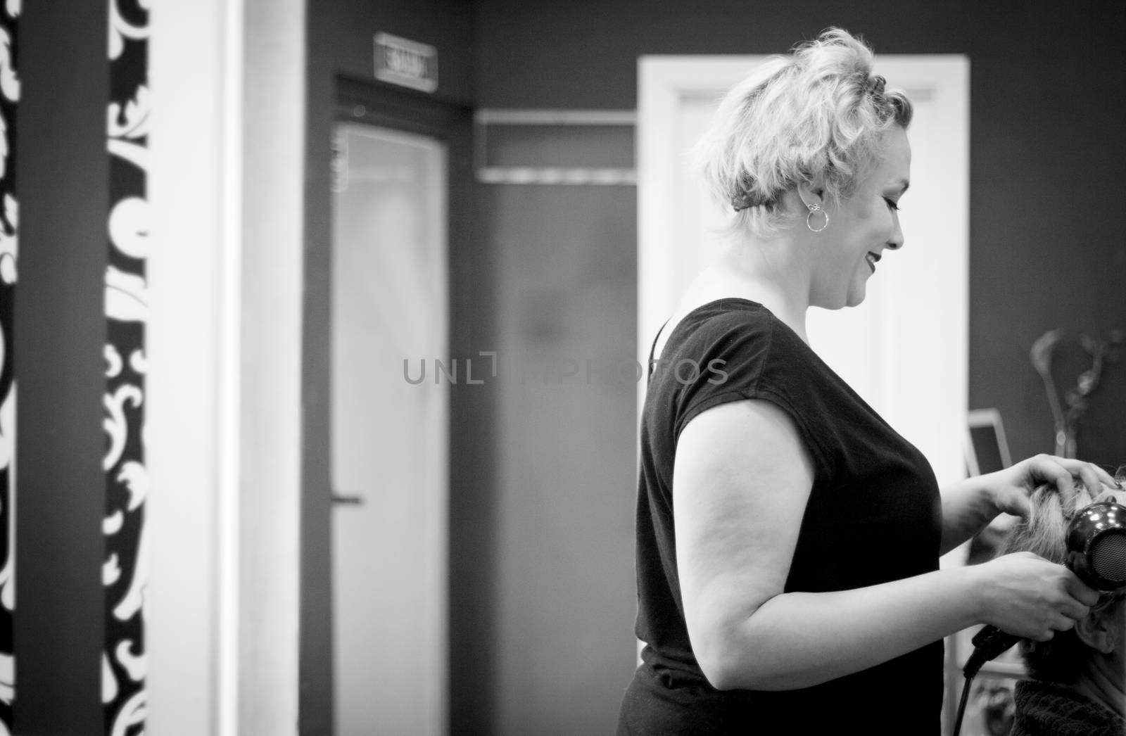 Hairdresser drying hair with red hand dryer