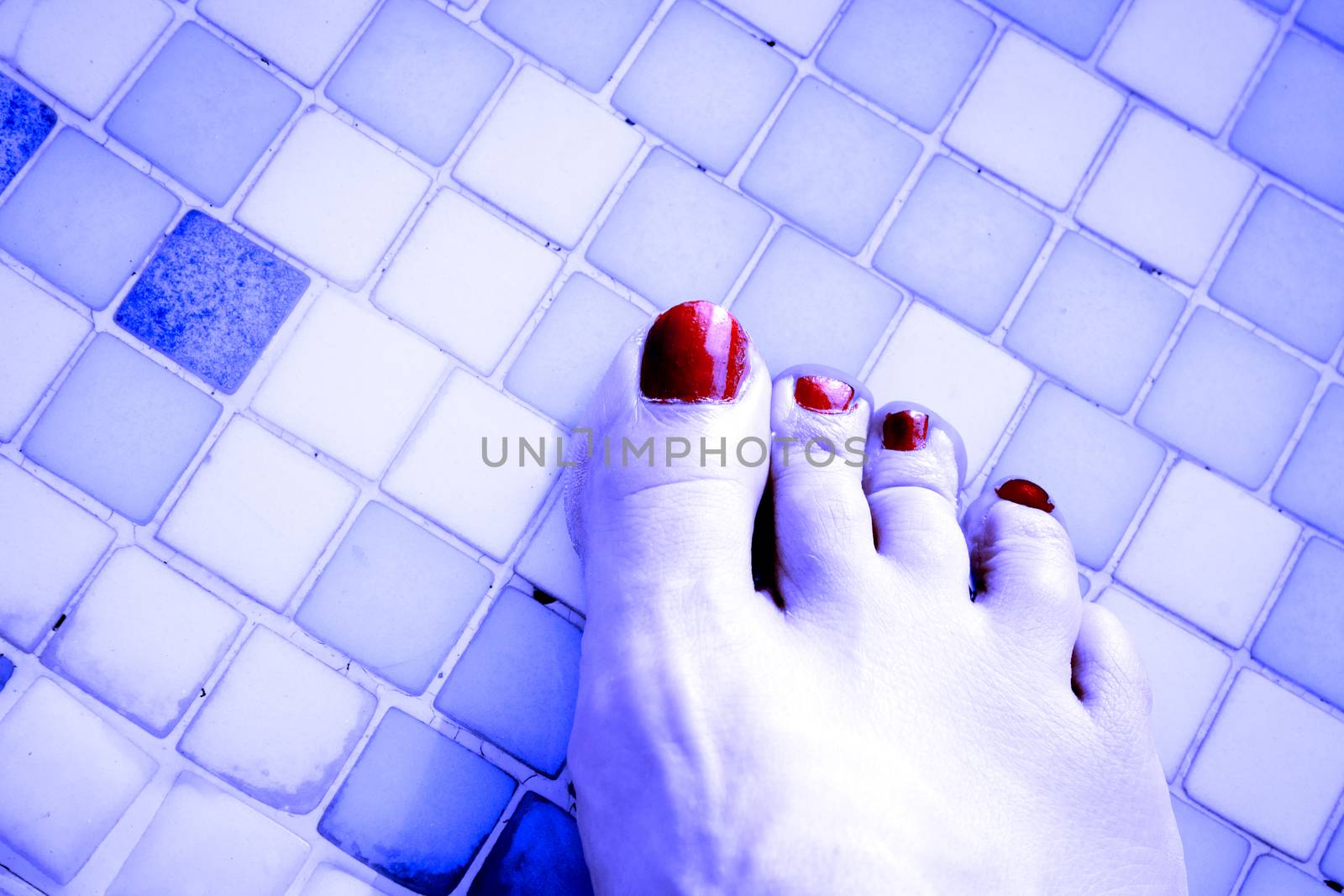 Bare feet of woman with nails painted red. Pool background