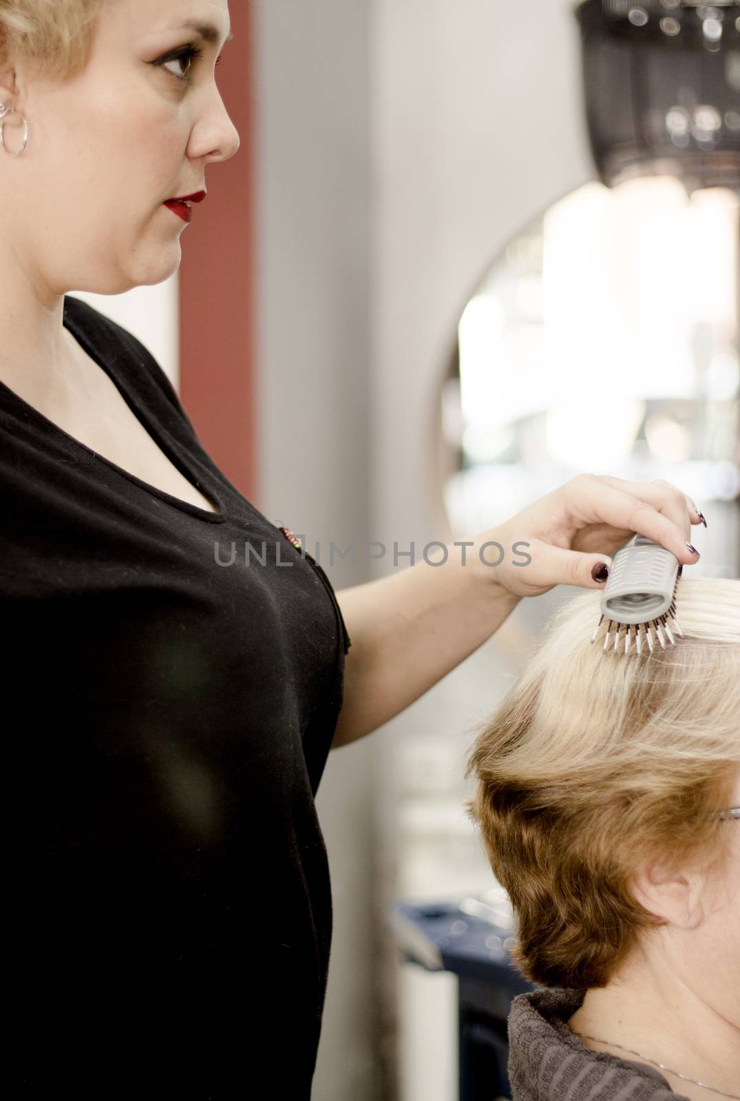 Hairdresser in positive attitude brushing the hair of a client
