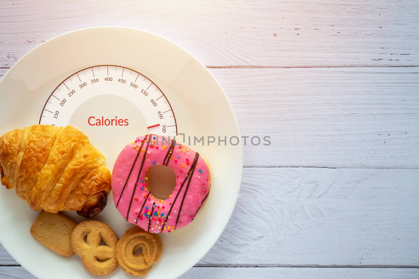 Calories counting and food control concept. doughnut ,croissant and cookies on white plate with tongue scales for Calories measuring
