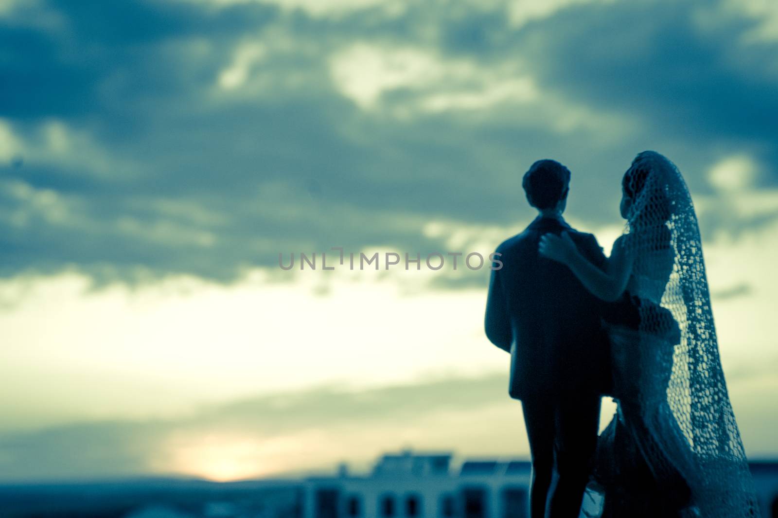 Silhouette of newlyweds with sunrise background. Romantic scene. Figures of the bridal cake, they are not real people