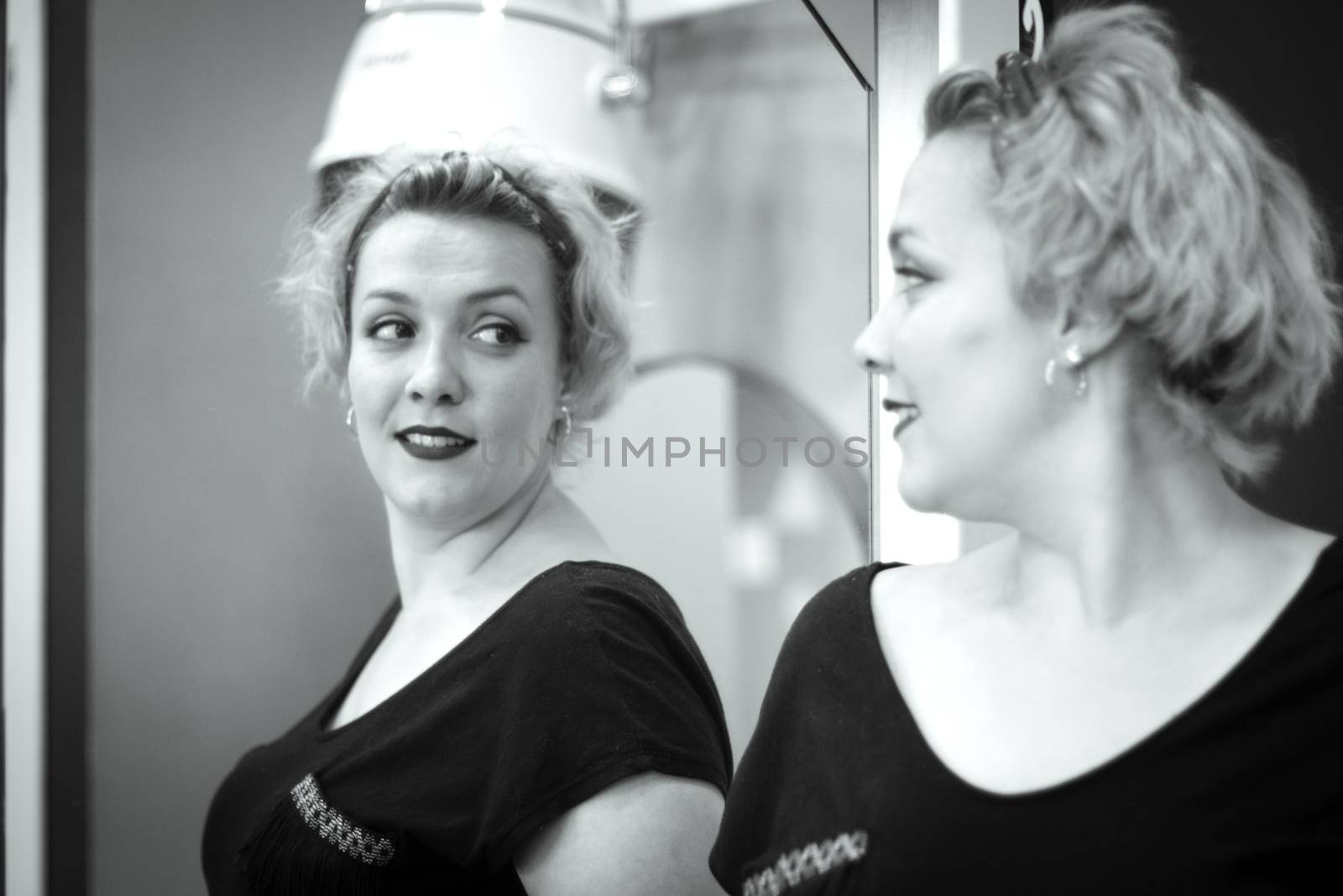 Blonde woman looking in the mirror of a hairdresser. Professional concept