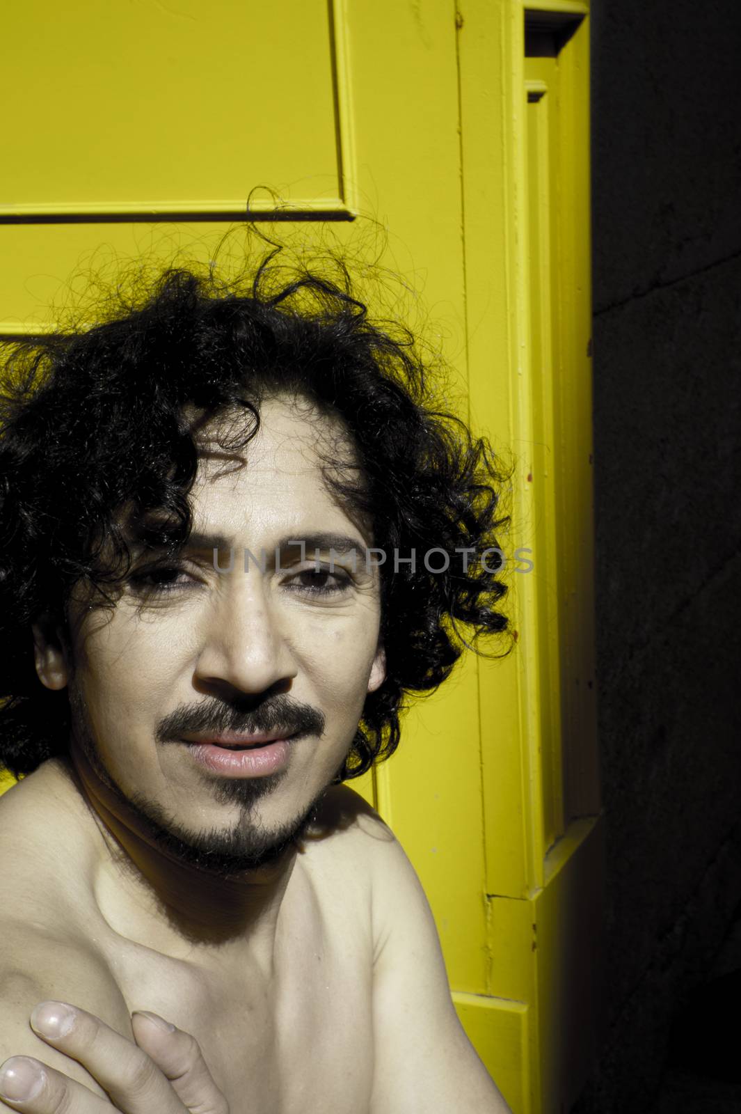 Portrait of latin man with beard and curly black hair. Naked torso