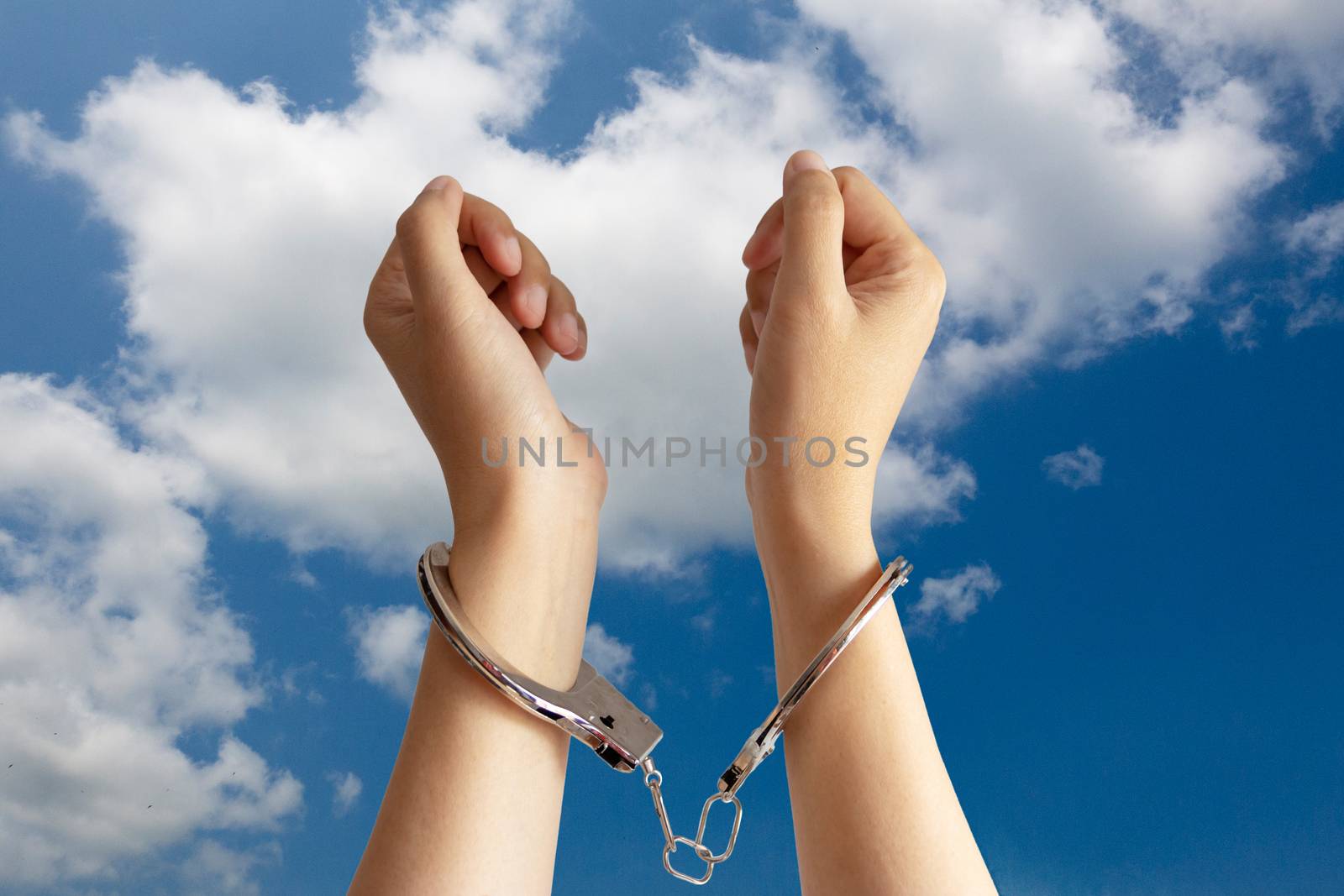 human trafficking ,slave labor and labor oppression problems concept. two hands was incarcerated by handcuff with blue sky at background