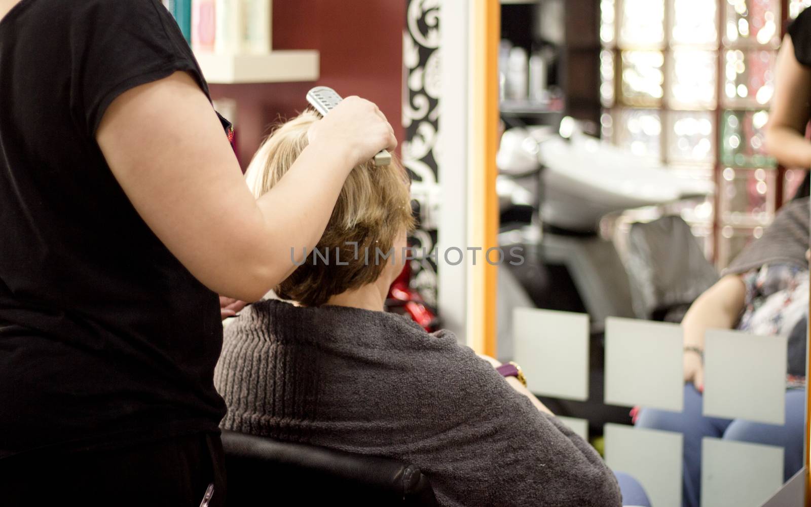 Hairdresser in positive attitude brushing the hair of a client