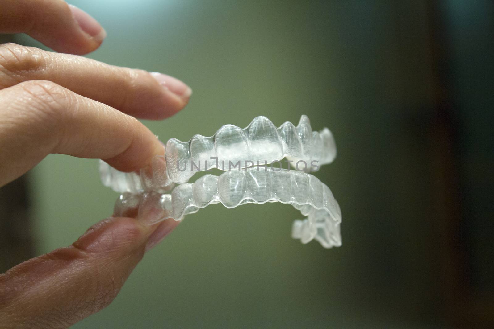 Womans hand holding transparent dental orthodontics to correct the dental alignment. Dark background