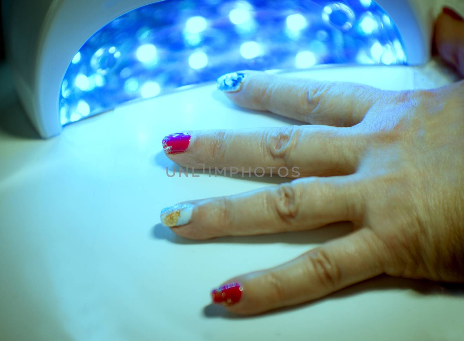 Womans hand drying nails with uv led lamp