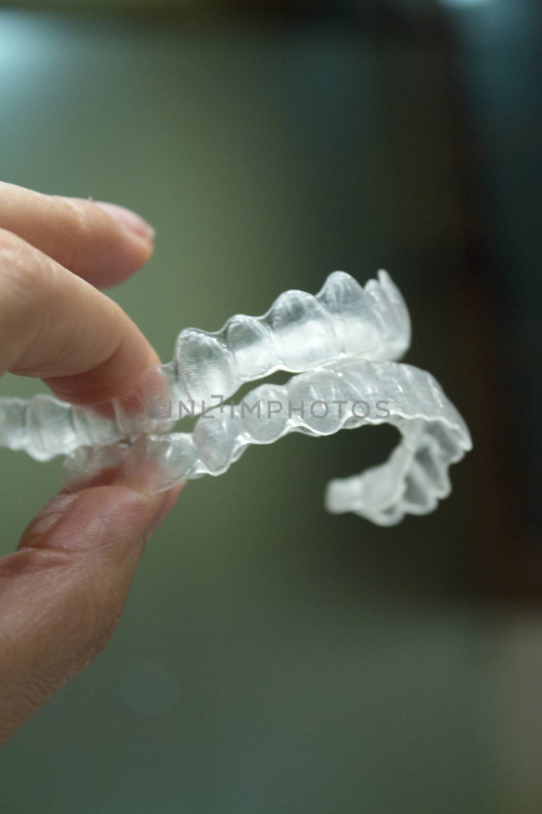 Womans hand holding transparent dental orthodontics to correct the dental alignment. Dark background