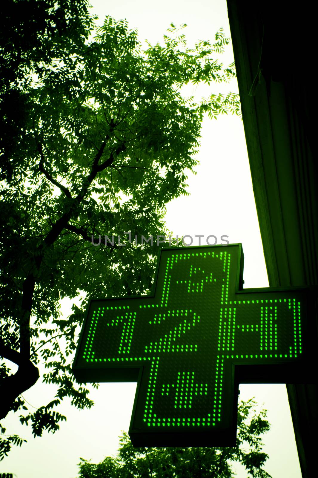 Pharmacy sign indicating open twelve hours. Green cross