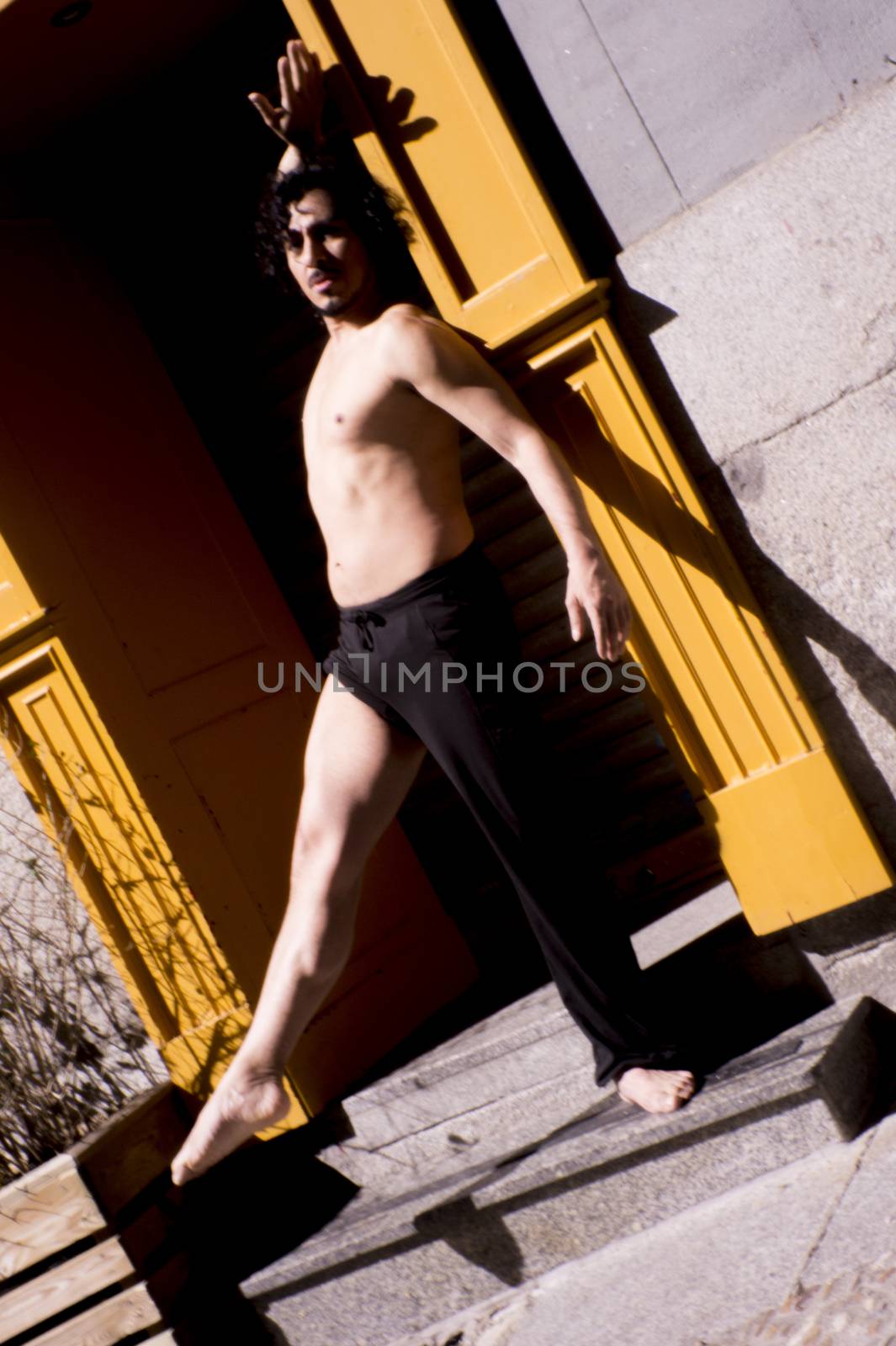 Latin male dancer posing with dancing figures. Urban background