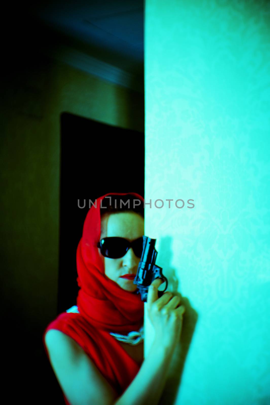 Woman dressed in red with dark glasses and gun in her hand