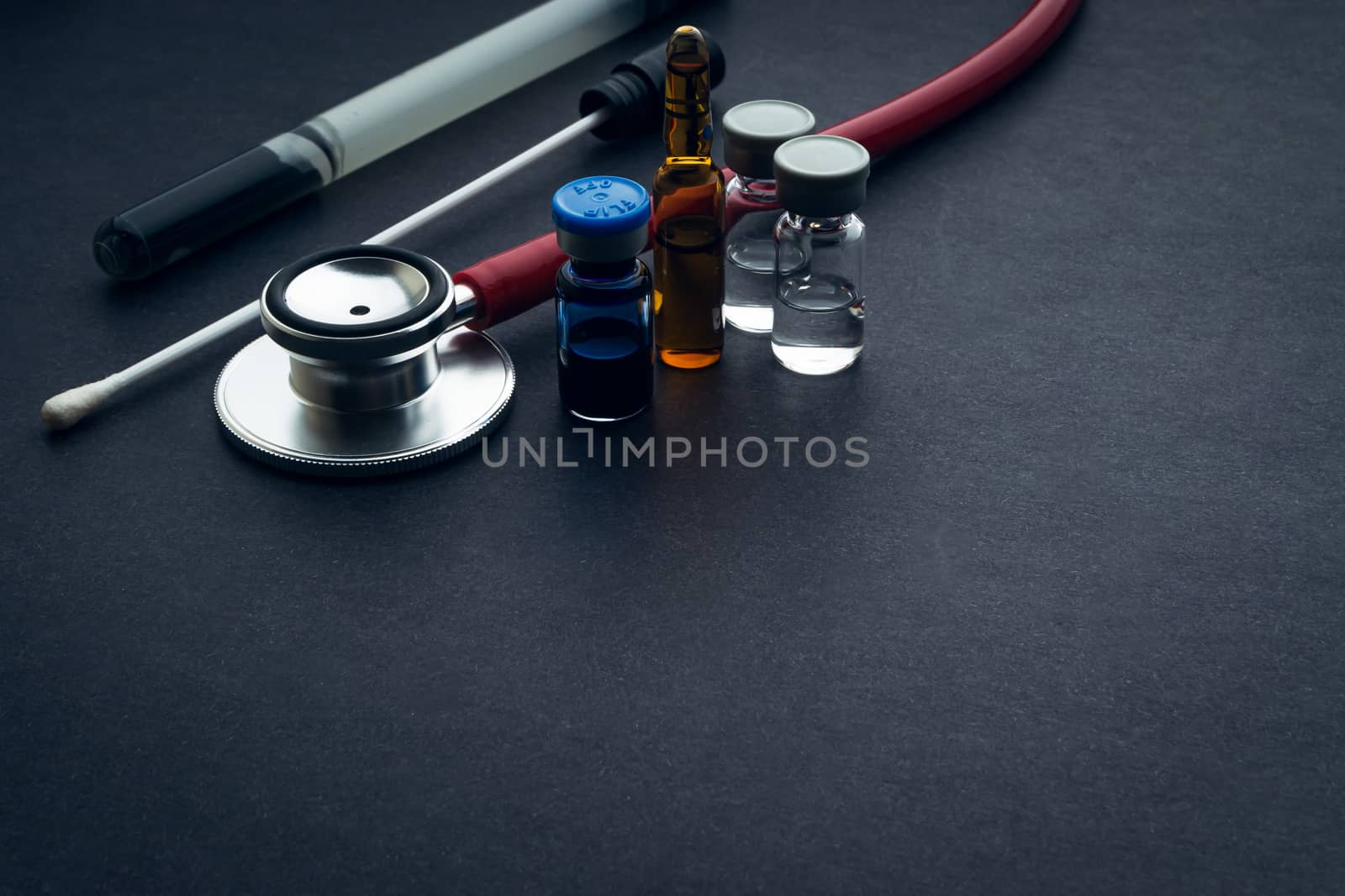 Medical swab, vials and stethoscope closeup on black background. Health care and copy space concept
