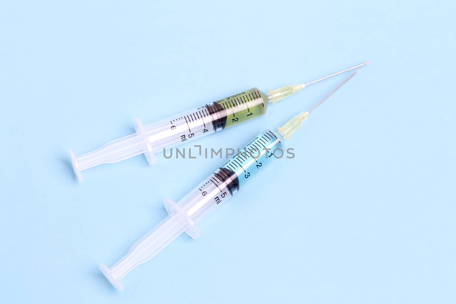 Syringe closeup with blue serum isolated on blue background.