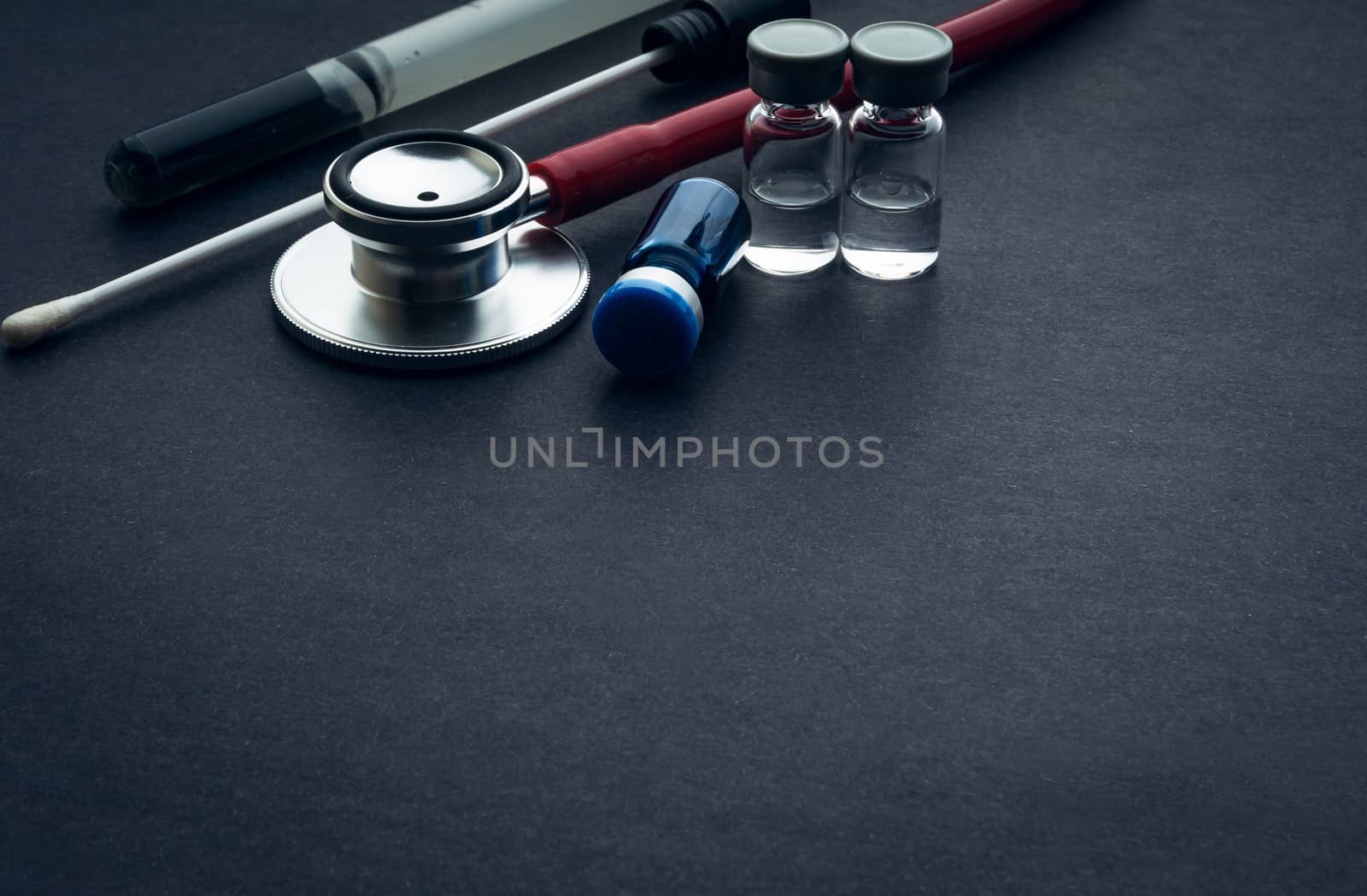 Medical swab, vials and stethoscope closeup on black background by silverwings