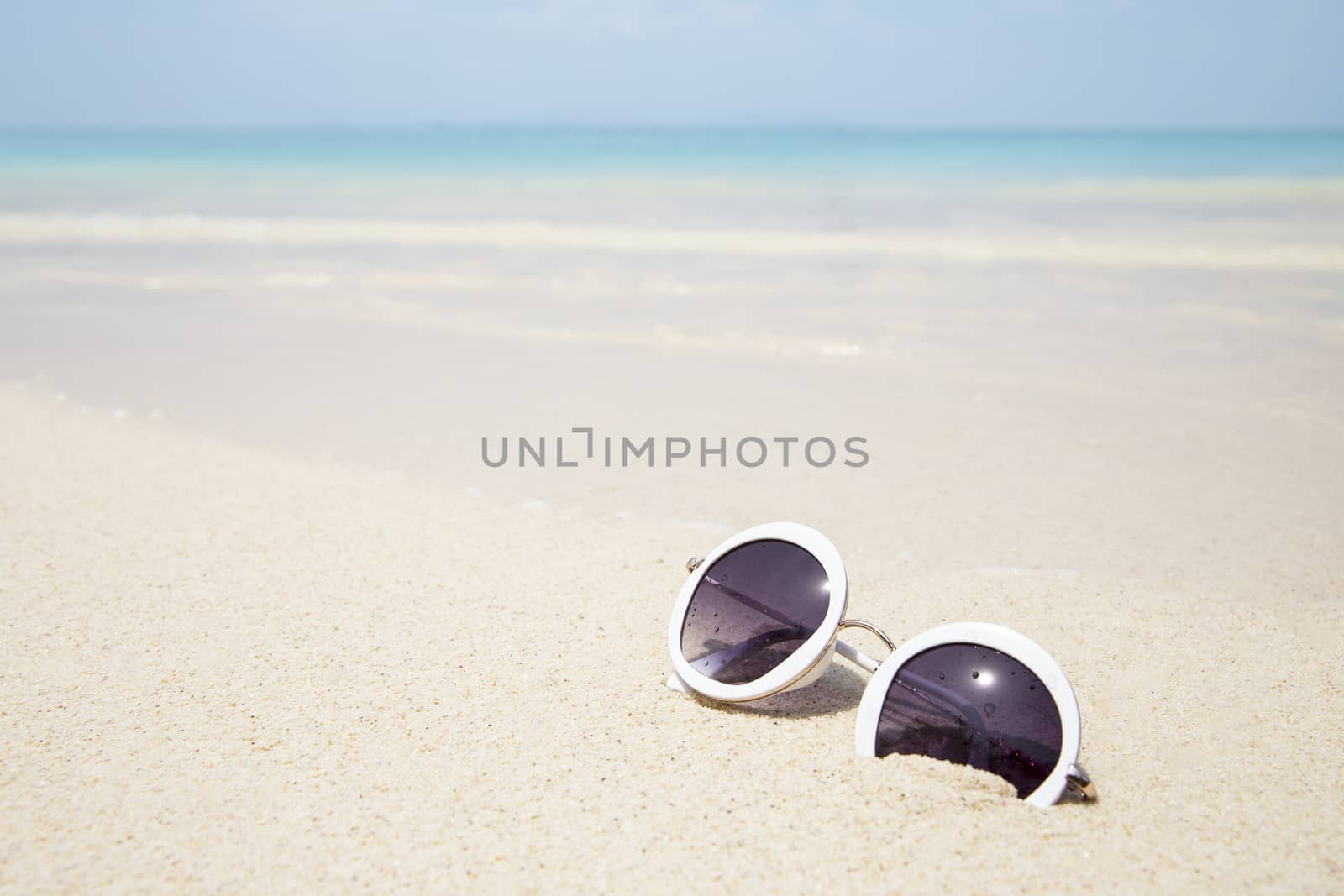 Sunglasses on sandy beach of blue sea in summer by Mizkit