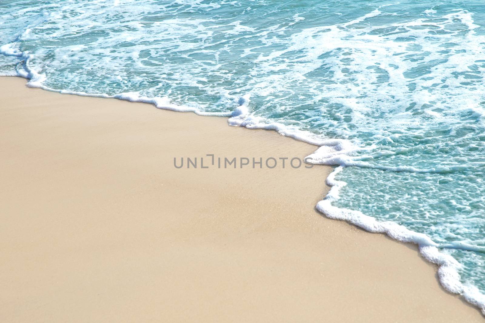 Soft wave and sea bubble of blue sea on sandy beach