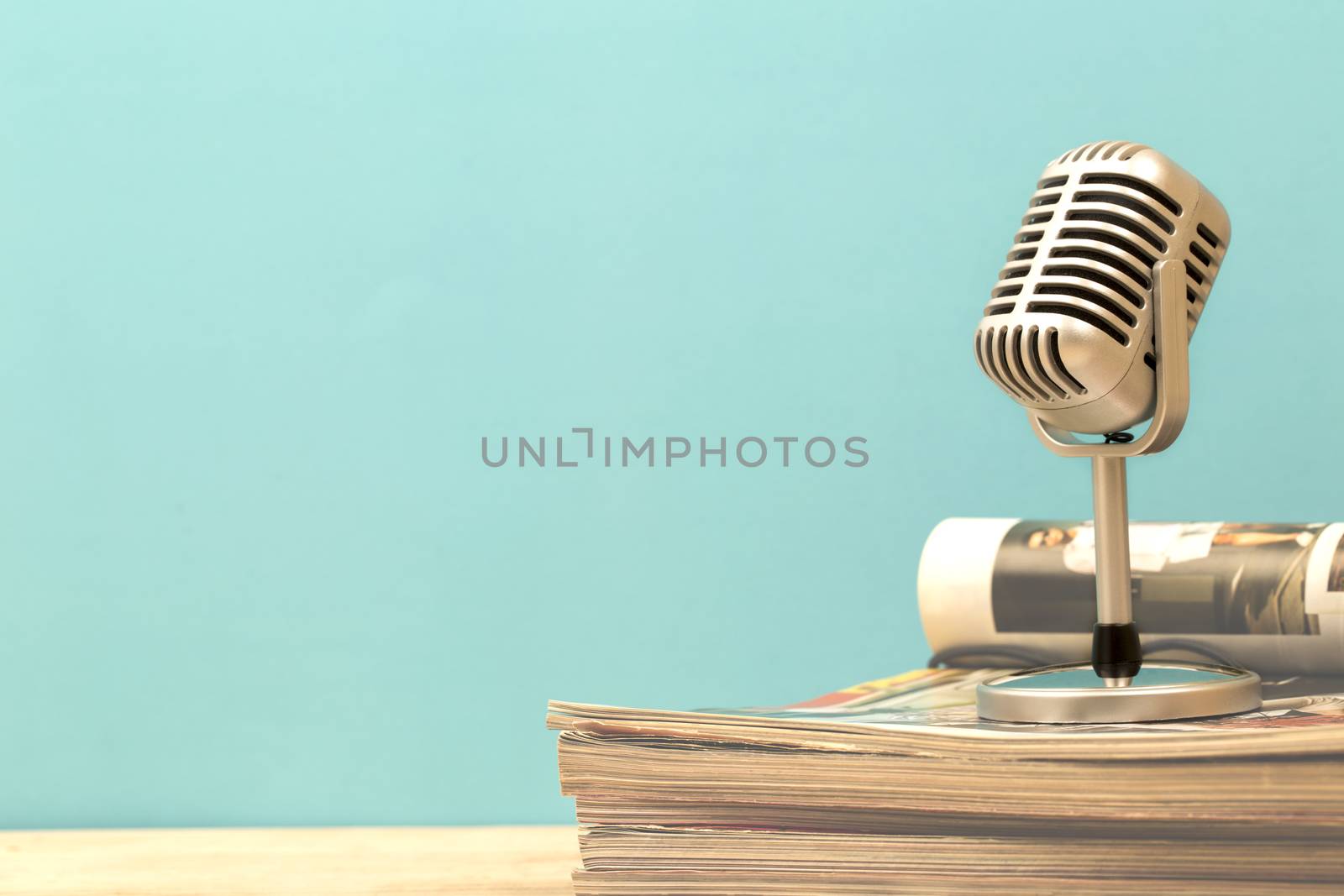 Retro microphone with old magazine on wooden table vintage stlye