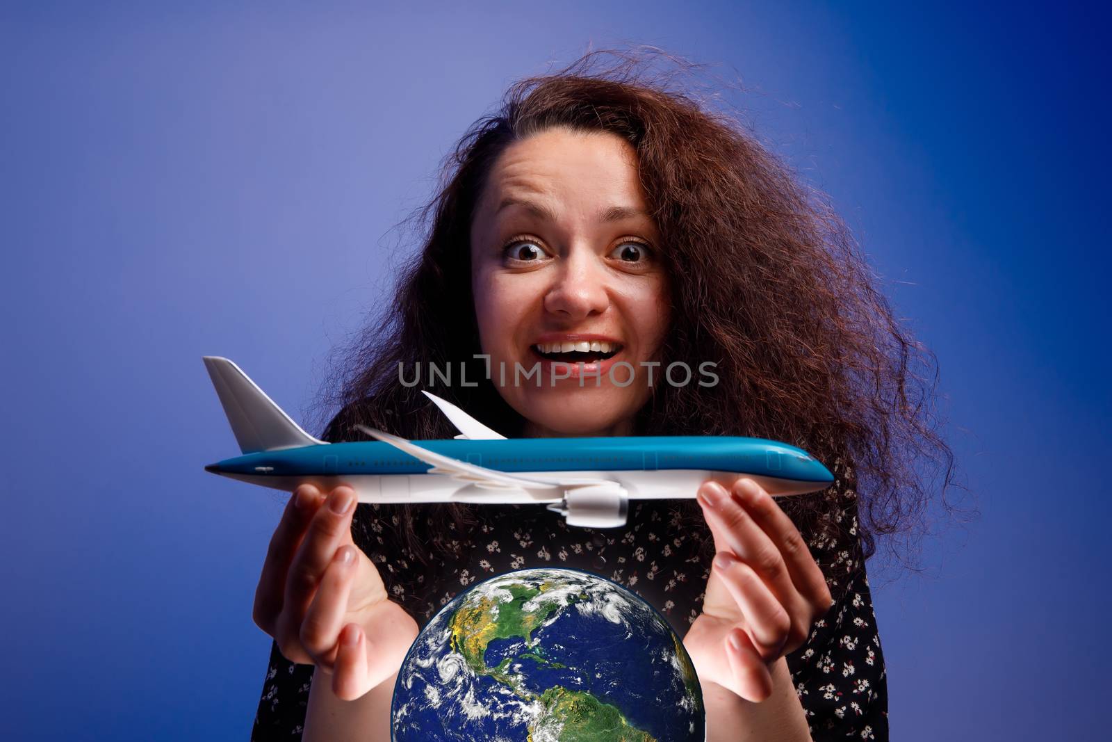 Girl with an airplane model in her arms over an earth globe. Concept of Airline help