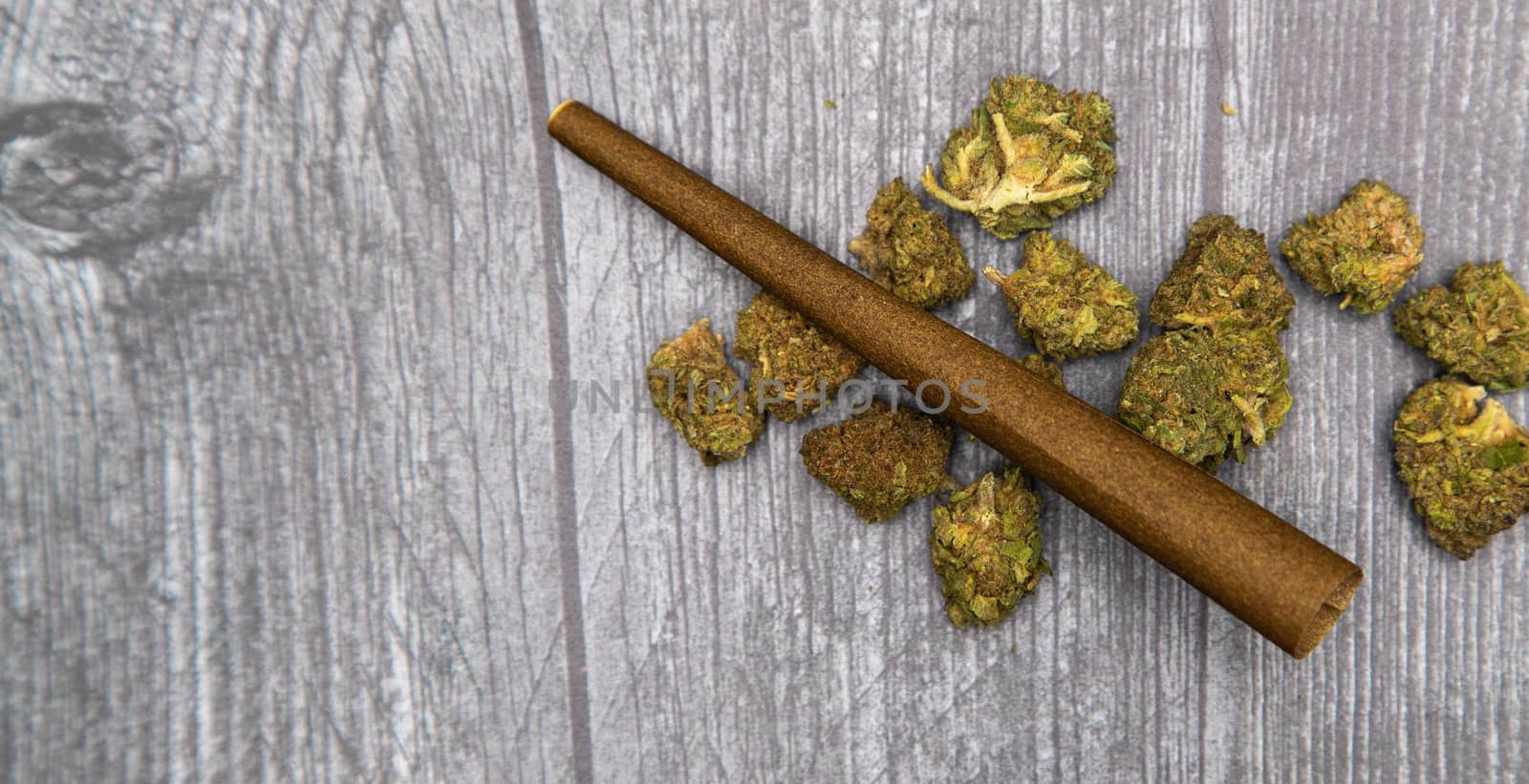 Several bright green medical marijuana buds on a wooden surface with a brown hemp wrap on top.