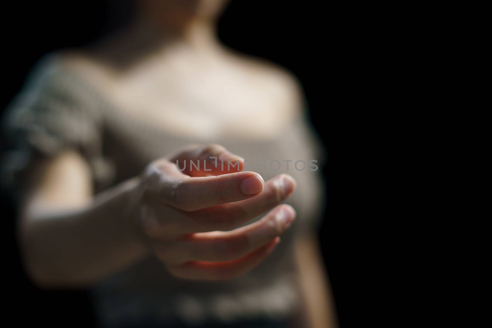 Woman open empty hand on black background.