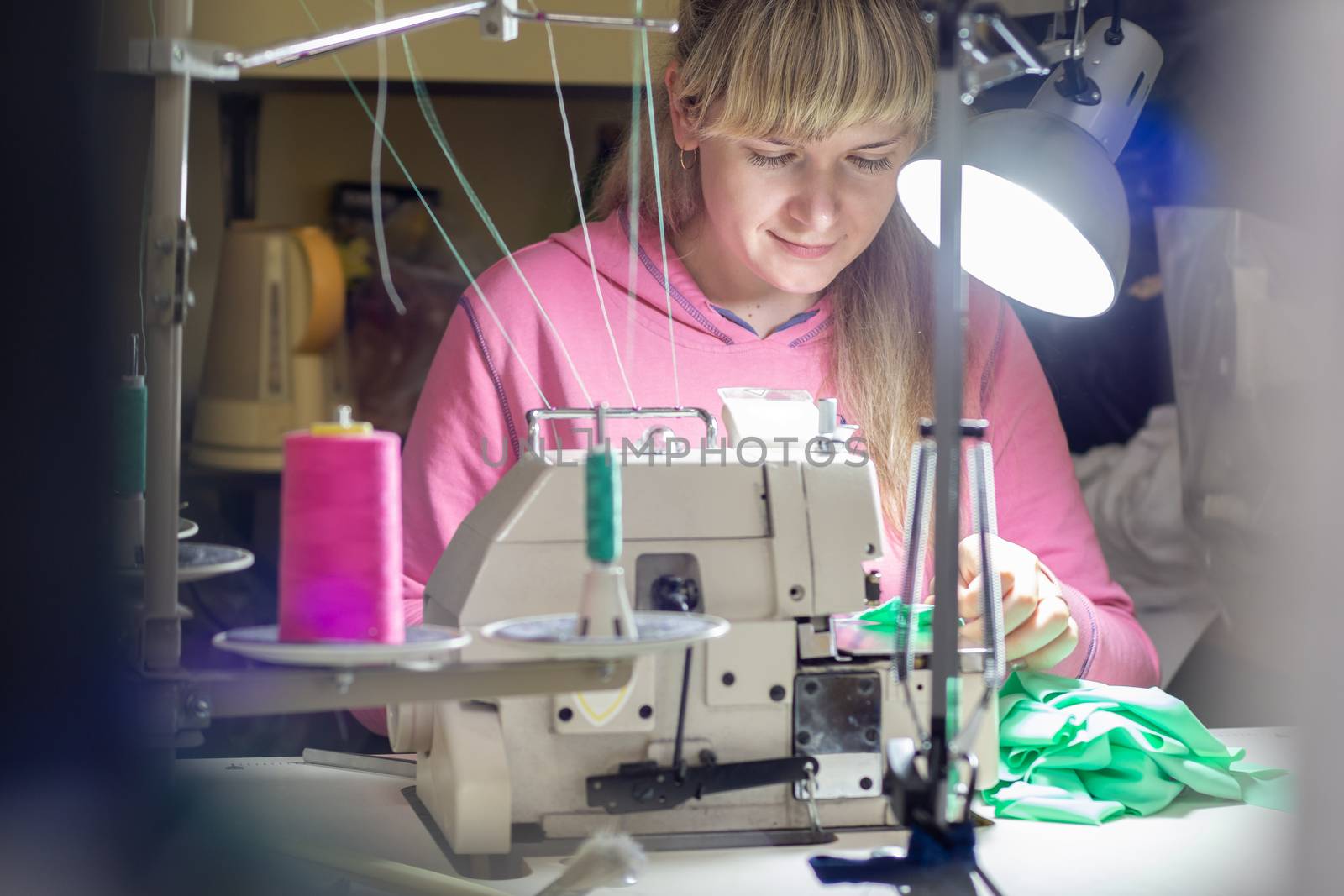 Girl works by light lamp behind industrial sewing machine