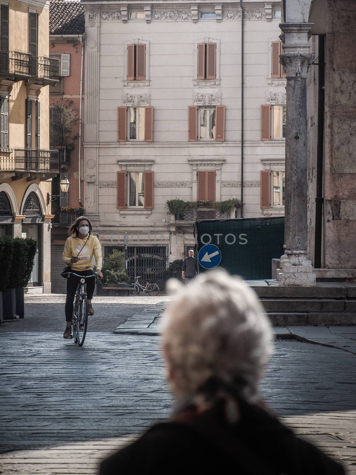 Cremona, Lombardy, Italy - May  5 6 7  2020 - man or woman walking or biking in deserted downtown  during covid outbreak lockdown phase 2