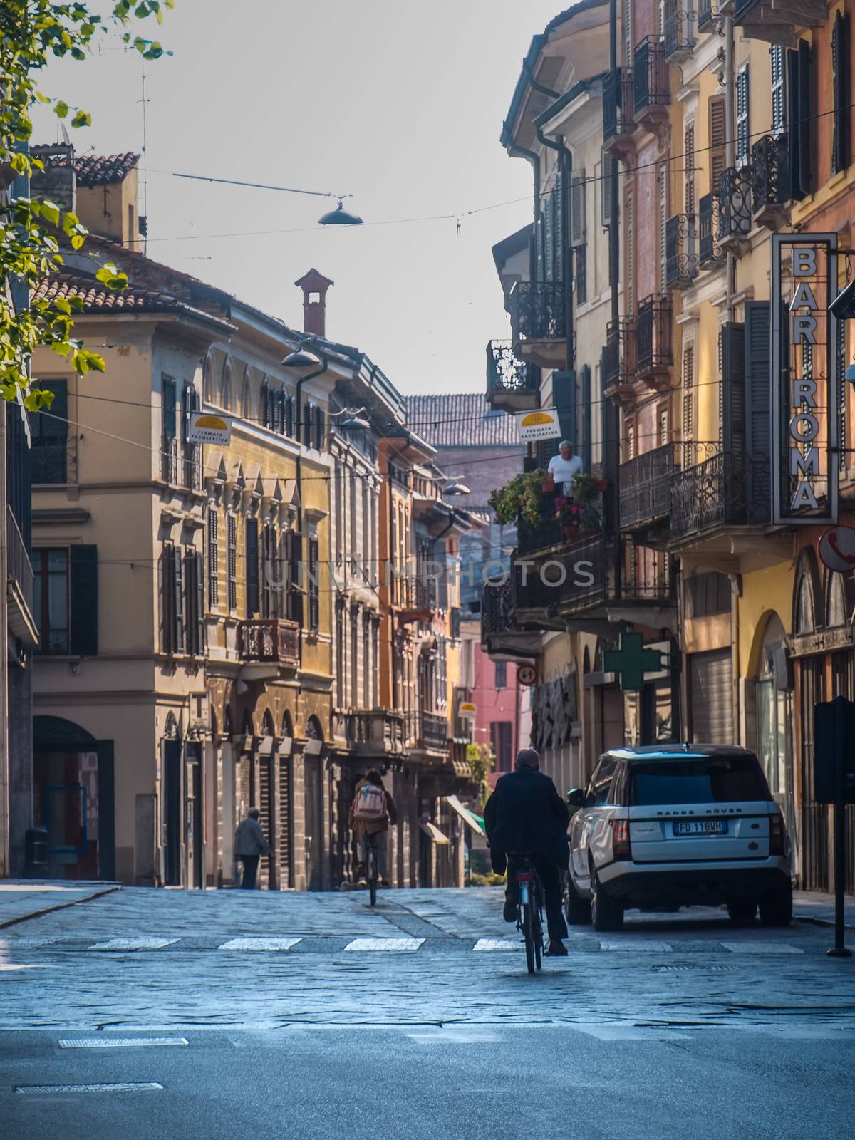 Cremona, Lombardy, Italy - May  5 6 7  2020 - man or woman walking or biking in deserted downtown  during covid outbreak lockdown phase 2
