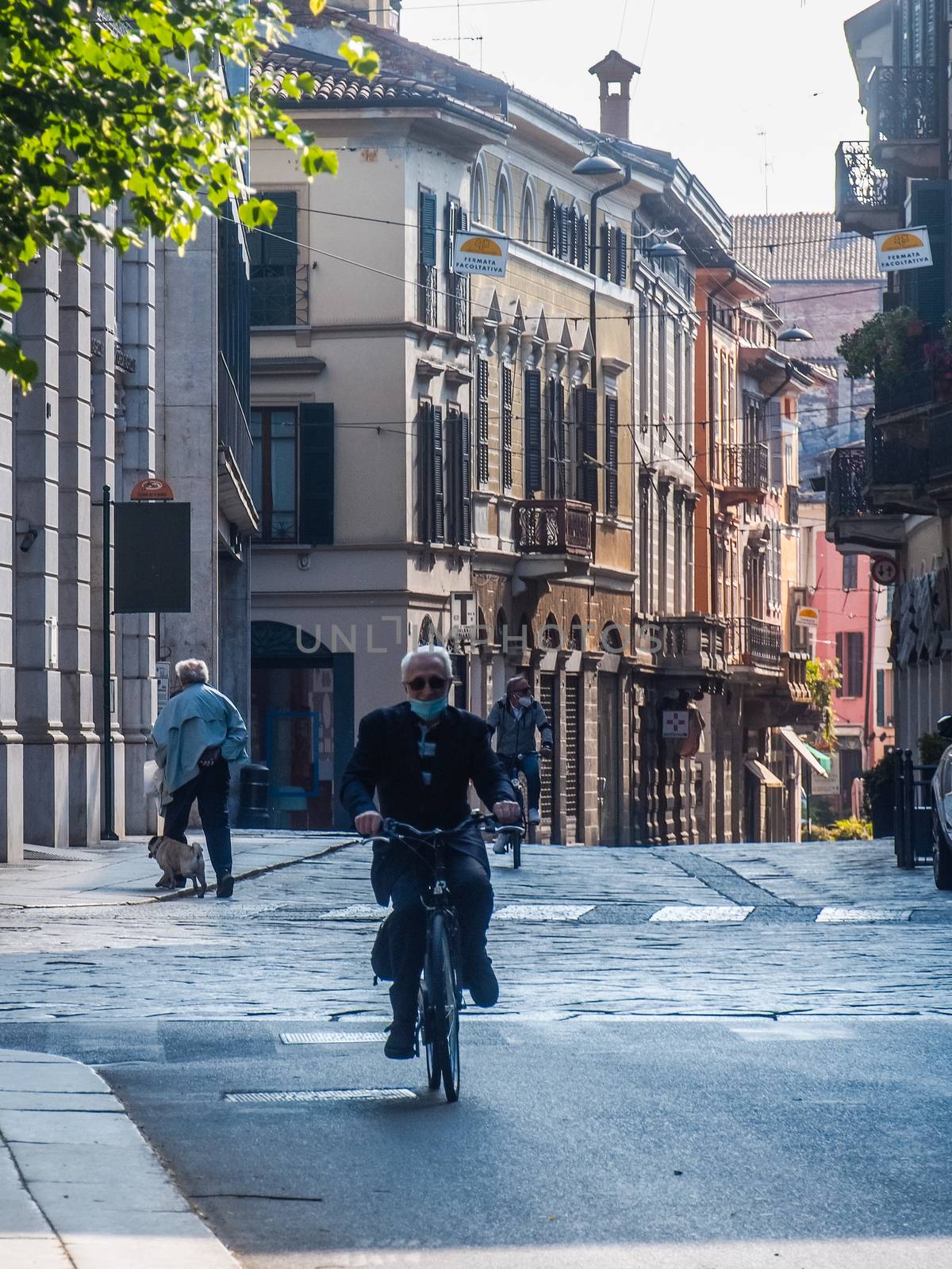 Cremona, Lombardy, Italy - May  5 6 7  2020 - man or woman walking or biking in deserted downtown  during covid outbreak lockdown phase 2
