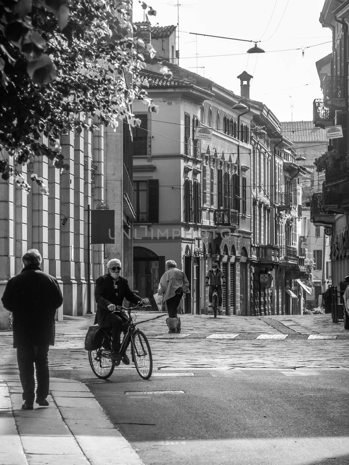 Cremona, Lombardy, Italy - May  5 6 7  2020 - man or woman walking or biking in deserted downtown  during covid outbreak lockdown phase 2