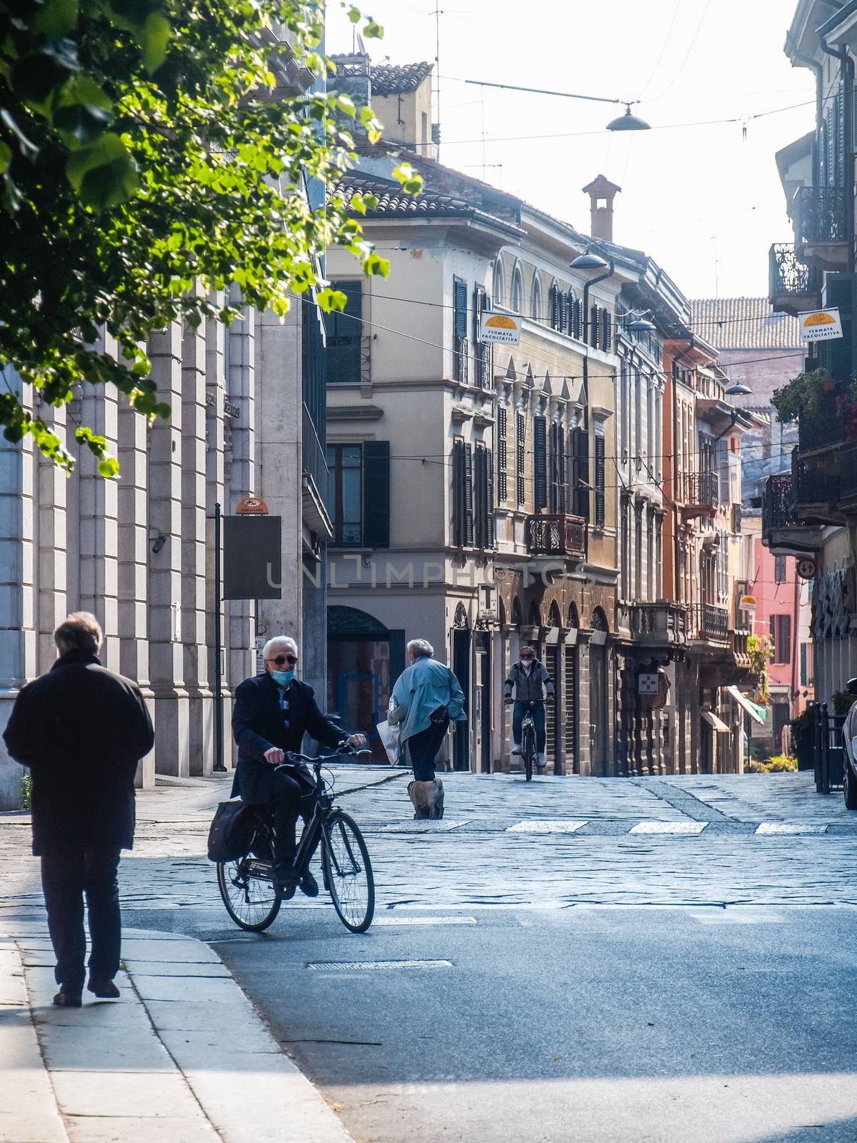 Cremona, Lombardy, Italy - May  5 6 7  2020 - man or woman walking or biking in deserted downtown  during covid outbreak lockdown phase 2