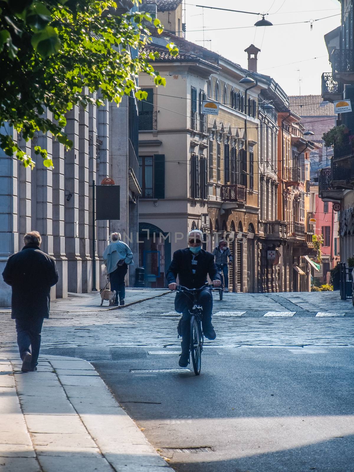 Cremona, Lombardy, Italy - May  5 6 7  2020 - man or woman walking or biking in deserted downtown  during covid outbreak lockdown phase 2