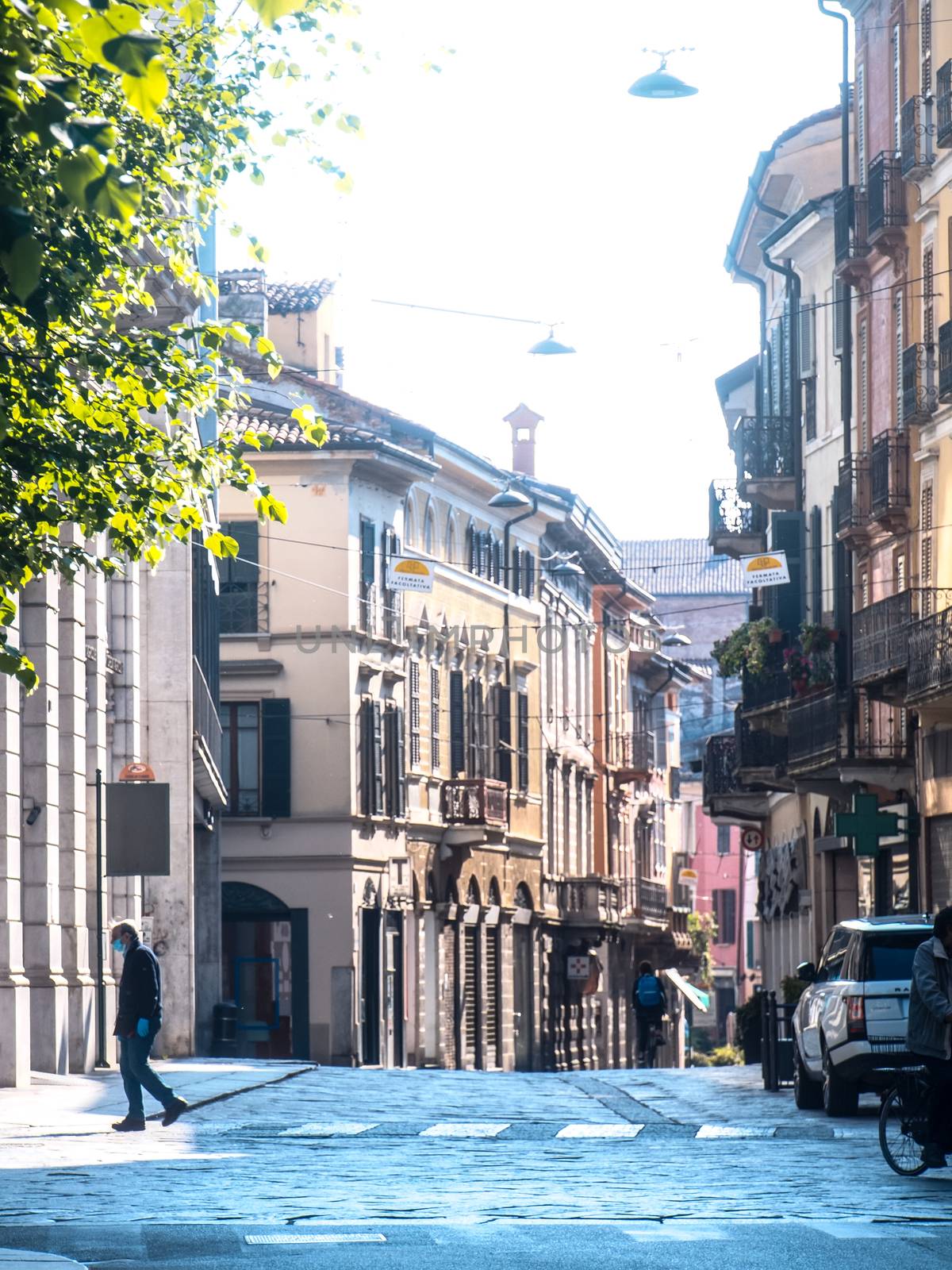 Cremona, Lombardy, Italy - May  5 6 7  2020 - man or woman walking or biking in deserted downtown  during covid outbreak lockdown phase 2