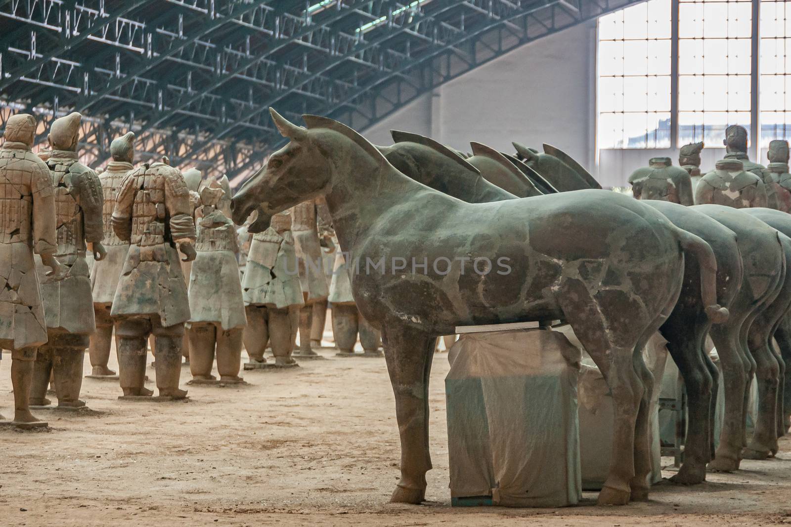 Xian, China - May 1, 2010: Terracotta Army museum and hall.  Gray-beige sculptures of row of horses and falanx of soldiers at excavation.