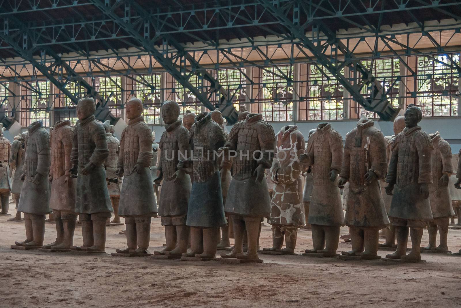 Xian, China - May 1, 2010: Terracotta Army museum and hall.  Gray-beige sculptures of falanx of soldiers, some with and some without heads at excavation.