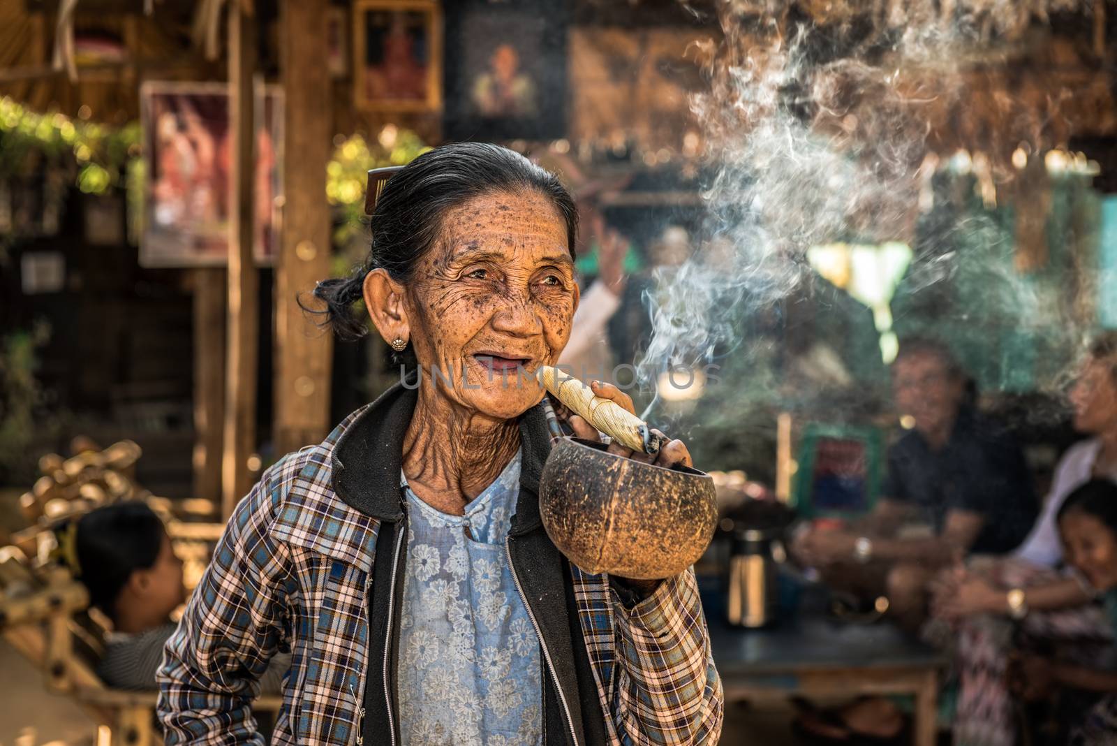 BAGAN, MYANMAR - JANUARY 24, 2016 : Happy and old wrinkled woman smokes a big cheroot cigar in public