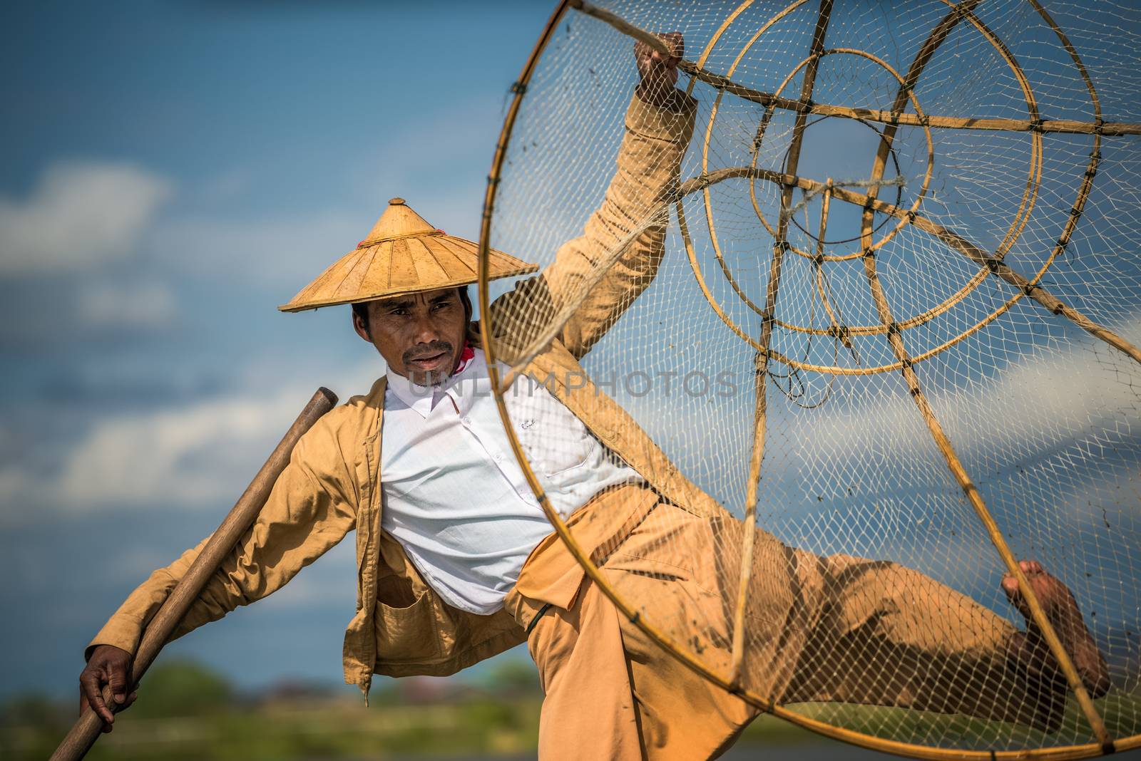 INLE LAKE, MYANMAR - JANUARY 26, 2016 : Close up of a burmese fisherman on a traditional bamboo boat using a handmade net