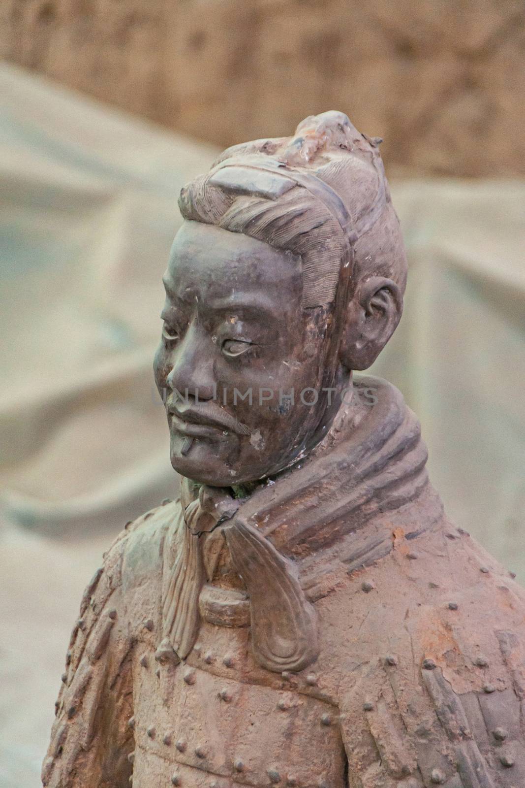 Xian, China - May 1, 2010: Terracotta Army museum and hall.  Front closeup on gray-dark sculpture of soldier at excavation.