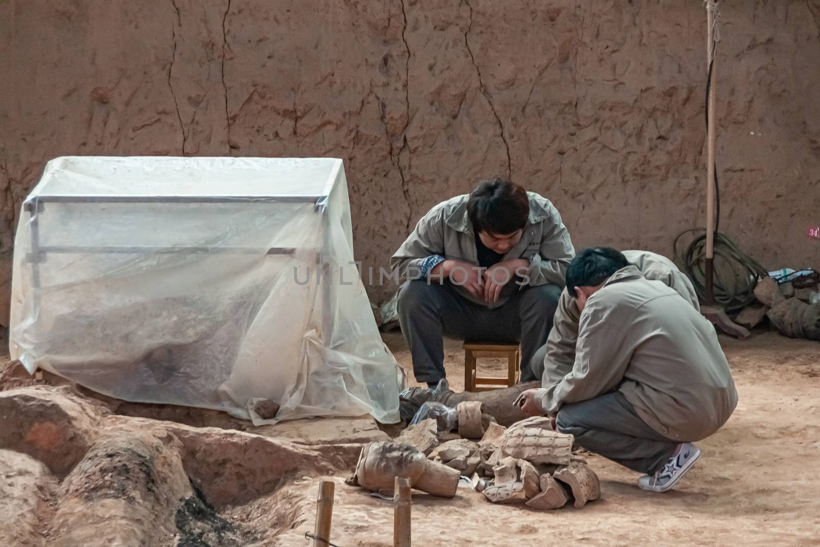 3 workers at excavation in Terracotta Army museum, Xian, China. by Claudine