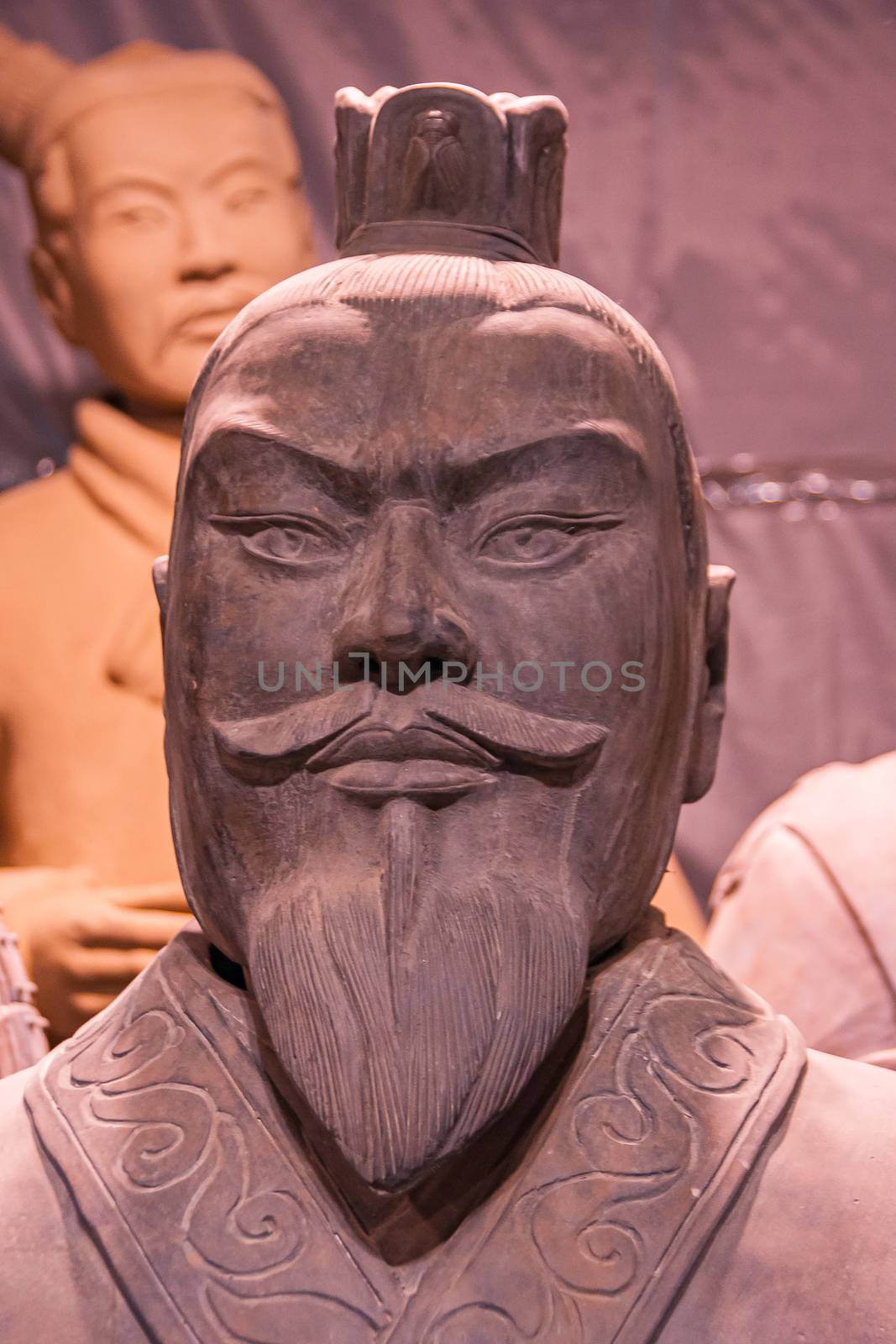 Xian, China - May 1, 2010: Terracotta Army museuml.  Closeup of reddish bearded head of officer sculpture with another one in faded back.