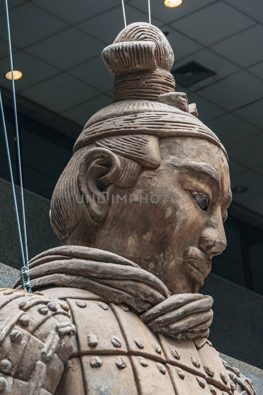 Xian, China - May 1, 2010: Terracotta Army museuml.  Head closeup of Giant light brown sculpture of officer in style. Ceiling as backdrop.