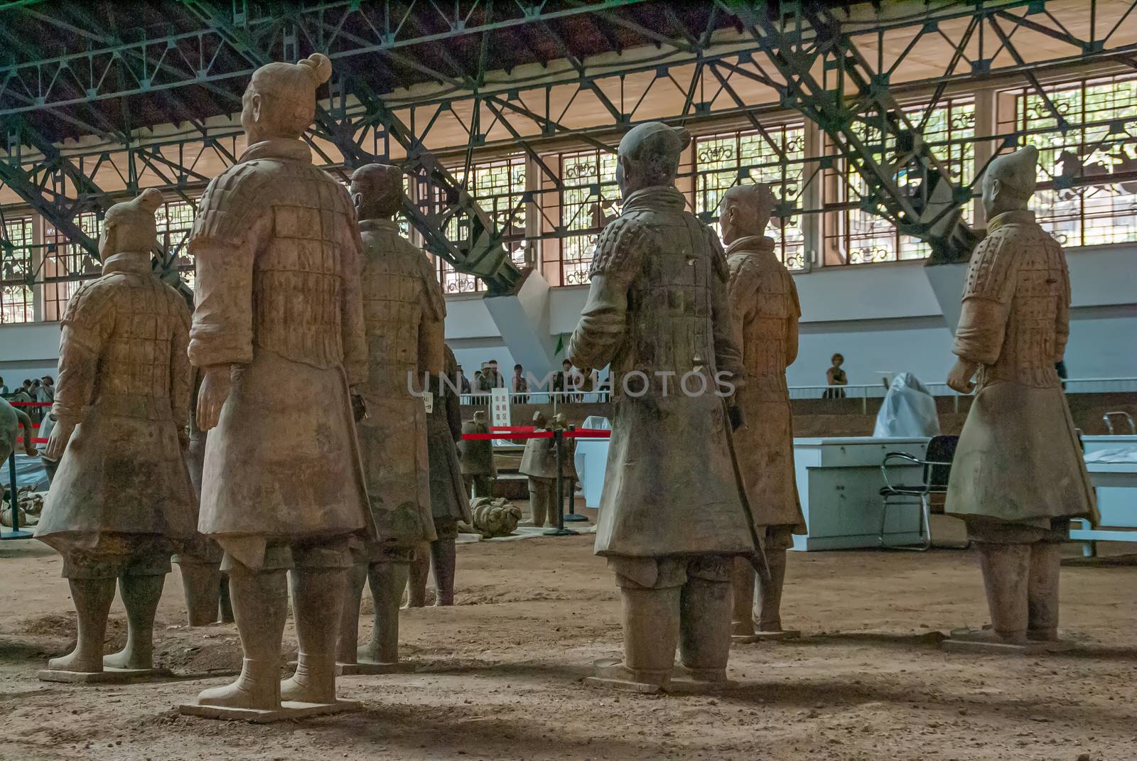 Xian, China - May 1, 2010: Terracotta Army excavation site. Group of Beige-gray statues of soldiers standing seen from back in large hall.