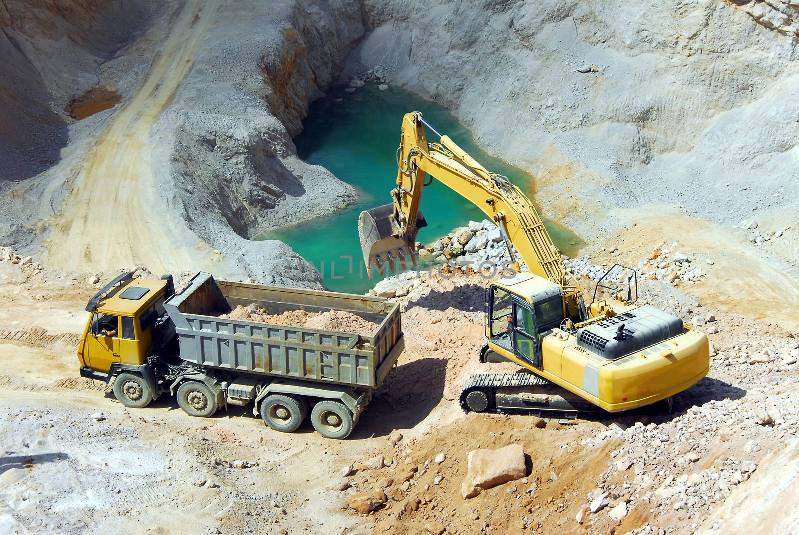 Yellow excavator loading stones in a truck