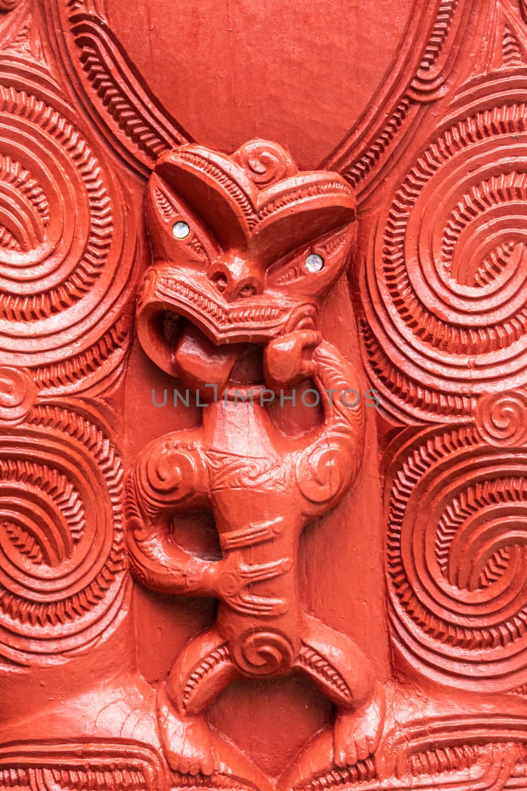 Laie, Oahu, Hawaii, USA. - January 09, 2020: Polynesian Cultural Center. Closeup of detail of red wooden sculpture showing small scary figure at New Zealand Maori hawaikiroa hall.