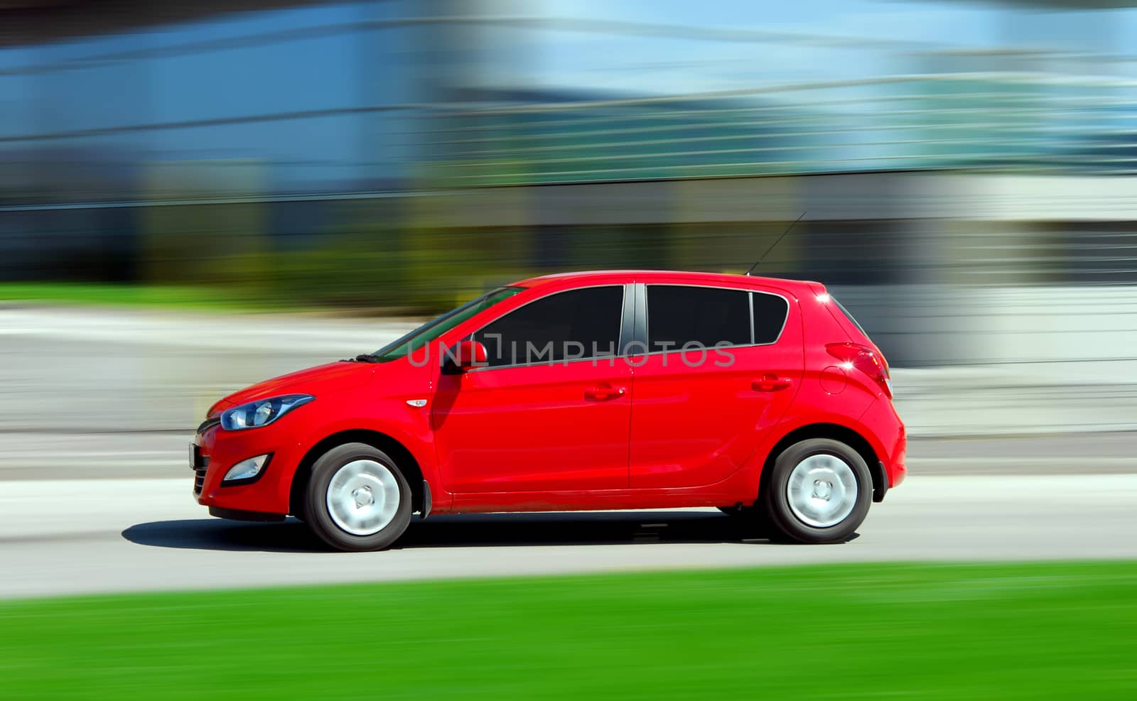 A panning shot of a speeding small red car