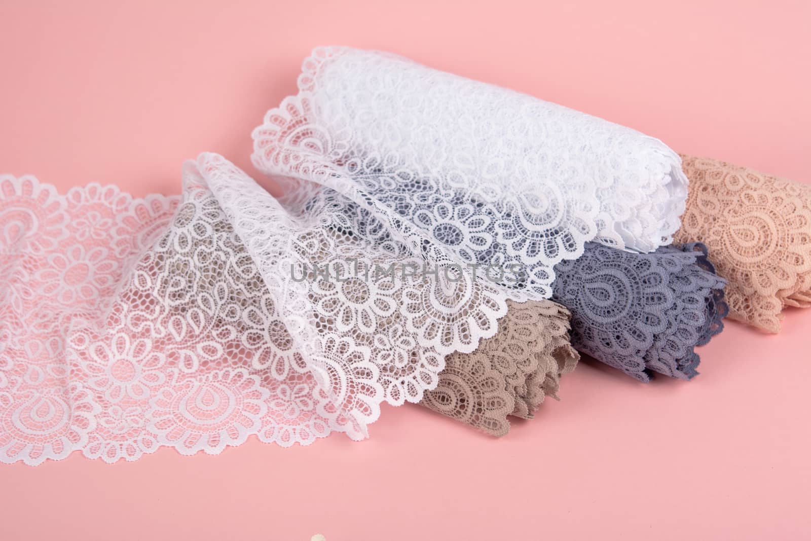 Roll of Delicate laces for panties and bras on pink background with plastic fittings. Elastic material. Using for Atelier and fabric store. by polyats