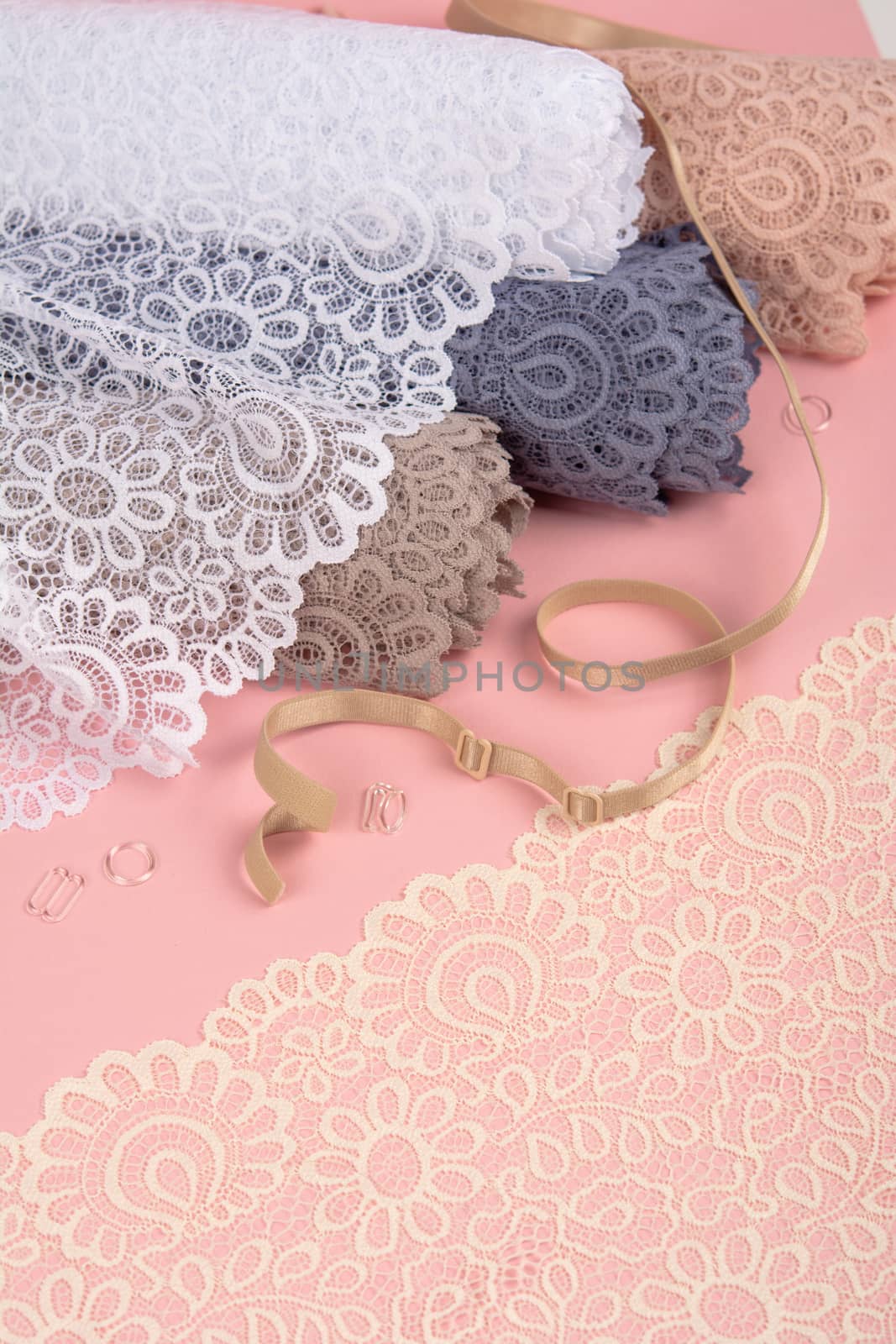 Roll of Delicate laces for panties and bras on pink background with plastic fittings. Elastic material. Using for Atelier and fabric store. by polyats